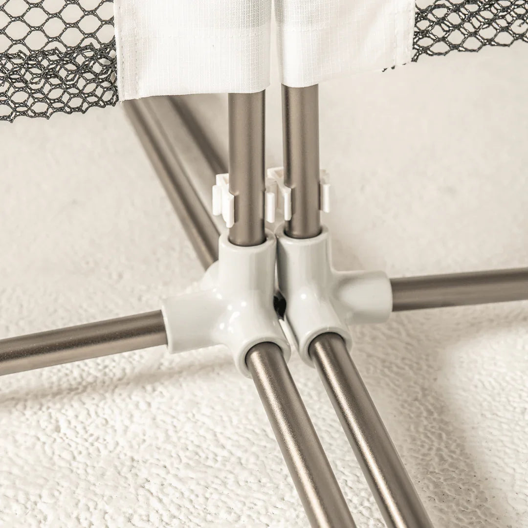 Sturdy metal playpen frame with white connectors and mesh fabric on textured floor