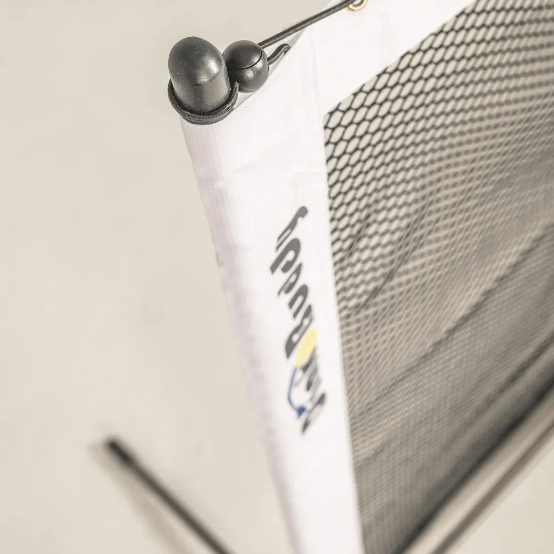 Close-up of a black mesh sports net with white border labeled 'ProBuddy' indoors