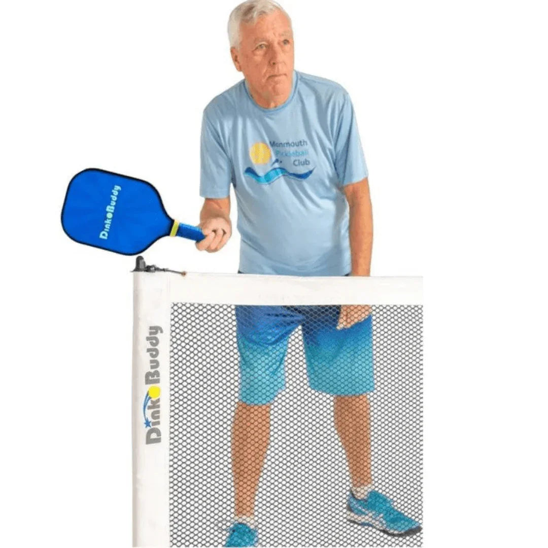 Older man playing pickleball with blue paddle and net, wearing Monmouth Pickleball Club shirt.